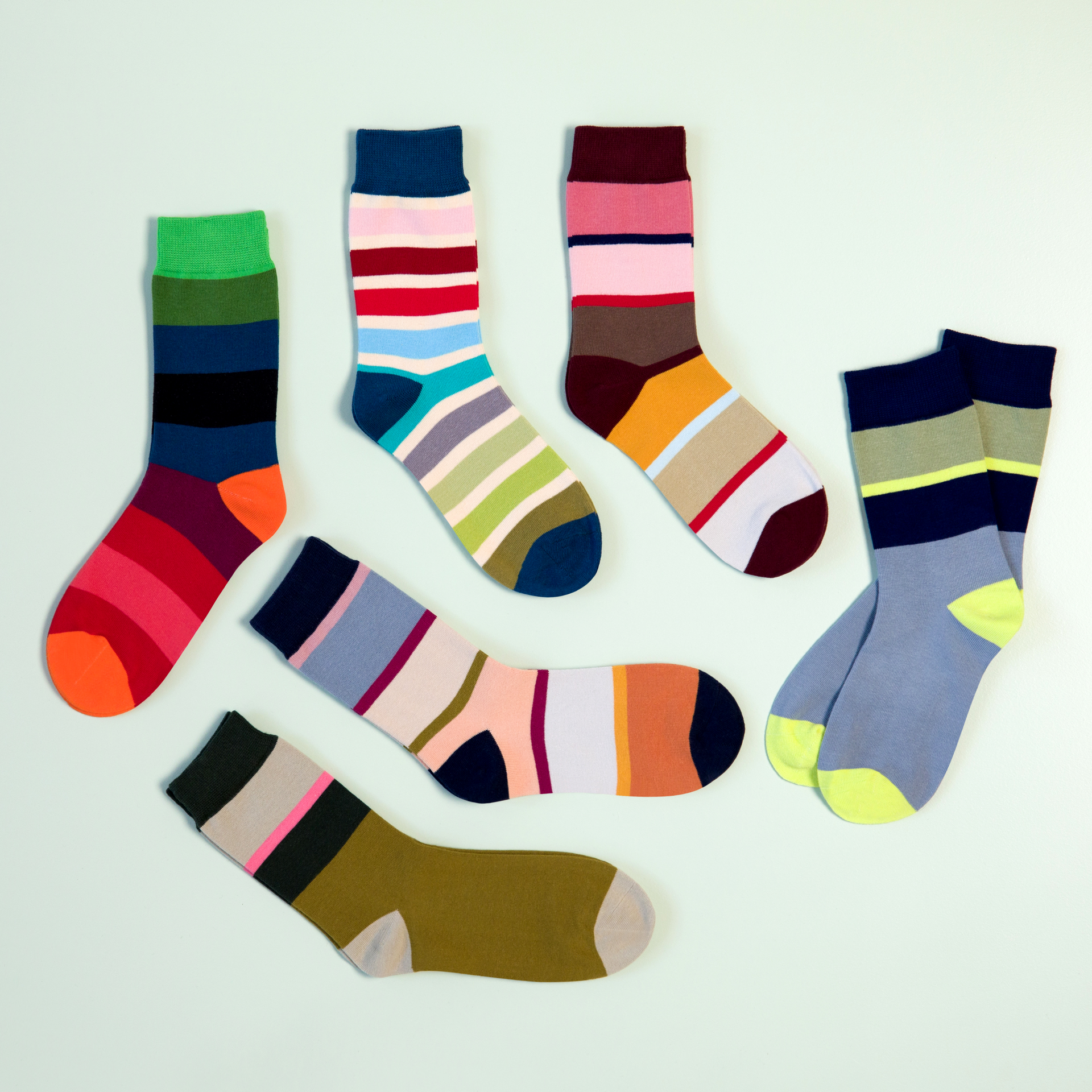 Varios calcetines de colores vivos, modelo 61, tallas 36-41, con motivos de rayas y bloques de color sobre fondo azul claro.