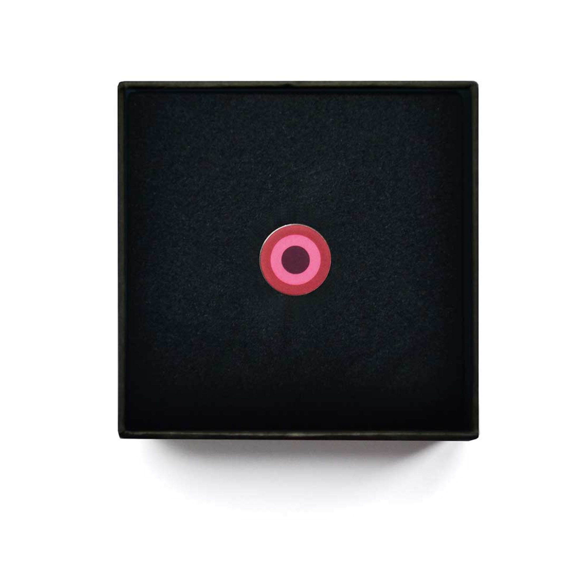 Pendentif noir en forme de bijou avec des cercles concentriques roses au centre.