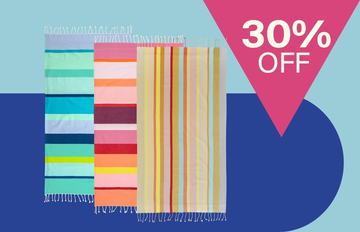 Drei bunte Strandtücher mit Fransen hängen vertikal vor zweifarbigem Hintergrund: links blau-grün gestreift, Mitte rosa-rot-orange, rechts gelb-rot-beige. Oben rechts ein pinkes Dreieck mit „30% OFF“.