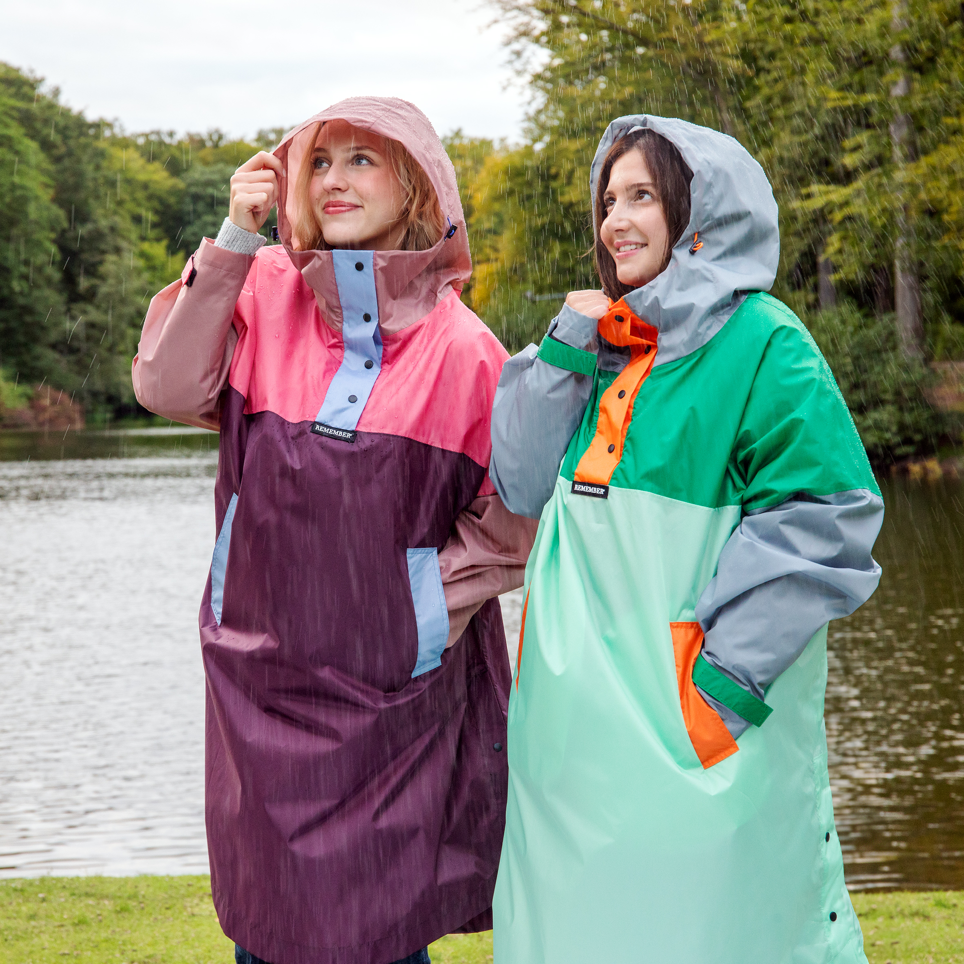 Dos mujeres llevan capas impermeables de la marca Ida bajo la lluvia. Las capas son coloridas, tienen capucha y bolsillos, y protegen de la lluvia.
