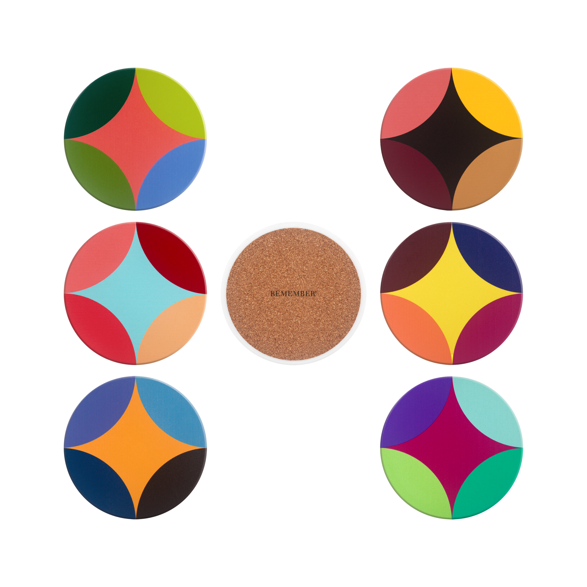 A set of six round ceramic coasters, each featuring a unique, colourful abstract design comprising four coloured segments and a central diamond shape. A seventh coaster is turned upside down to reveal the cork underside bearing the words ‘REMEMBER’.