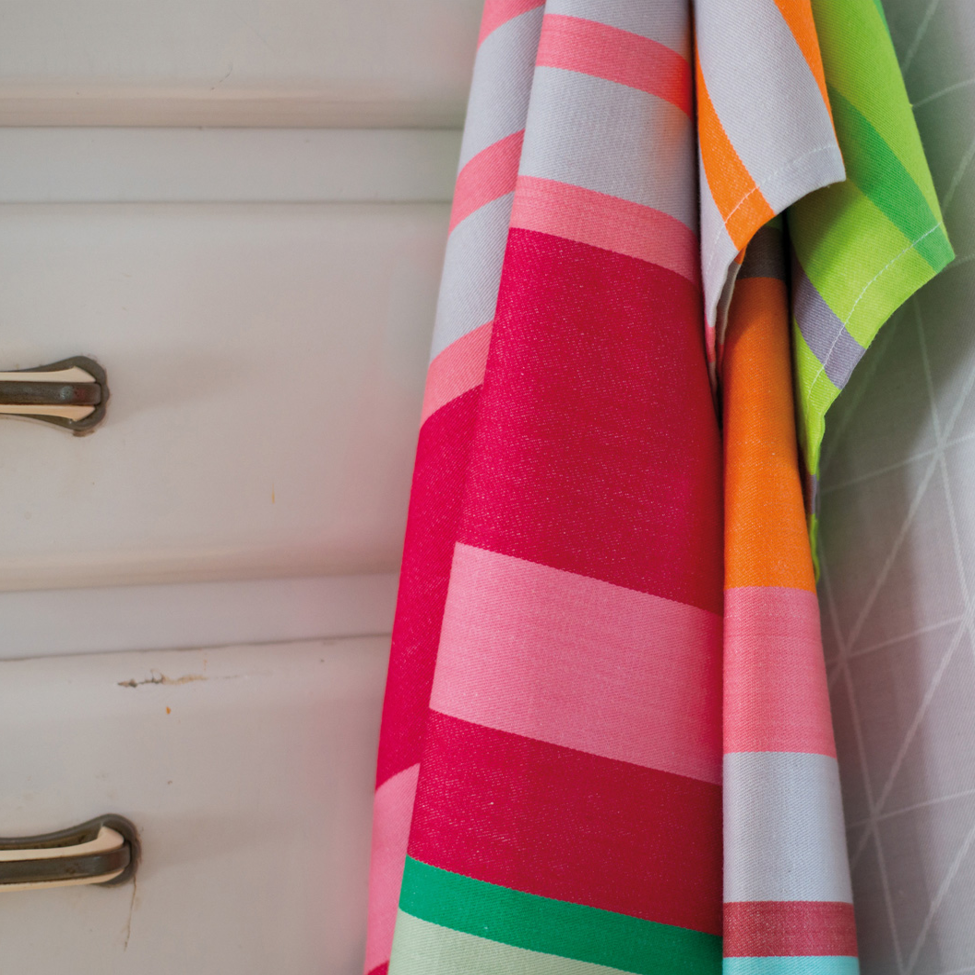 Gros plan sur des chiffons de séchage du set n° 16 avec des rayures colorées devant une armoire blanche.