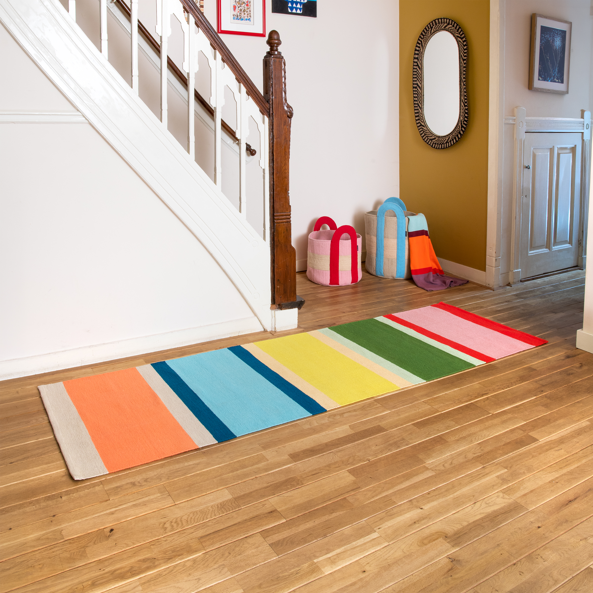 Langer, handgewebter Teppichläufer mit buntem Streifenmuster. Breite vertikale Streifen in Rosa, Grün, Gelb, Hellblau und Orange, akzentuiert durch schmale rote, beige, hellorange und dunkelblaue Linien. Aus reiner Baumwolle.