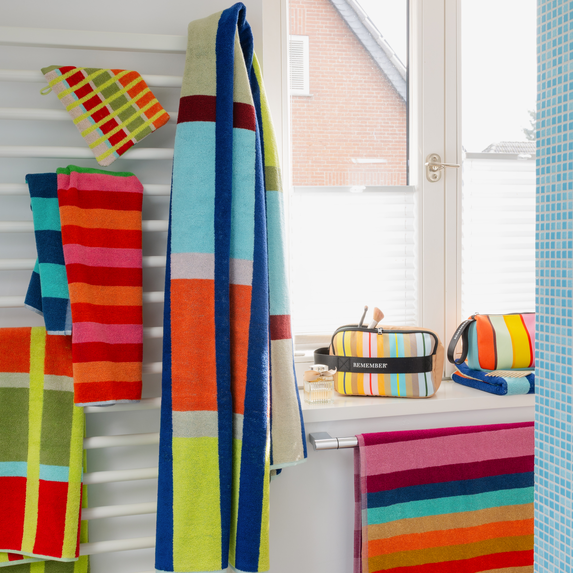 Yoku Badetuch mit farbenfrohem Karomuster. Breite dunkelblaue Längsstreifen kreuzen sich mit horizontalen Bändern in Weiß, Hellblau, Gelb, Rotorange und Beige-Grün. Flauschige Baumwolltextur, extragroß und saugfähig.