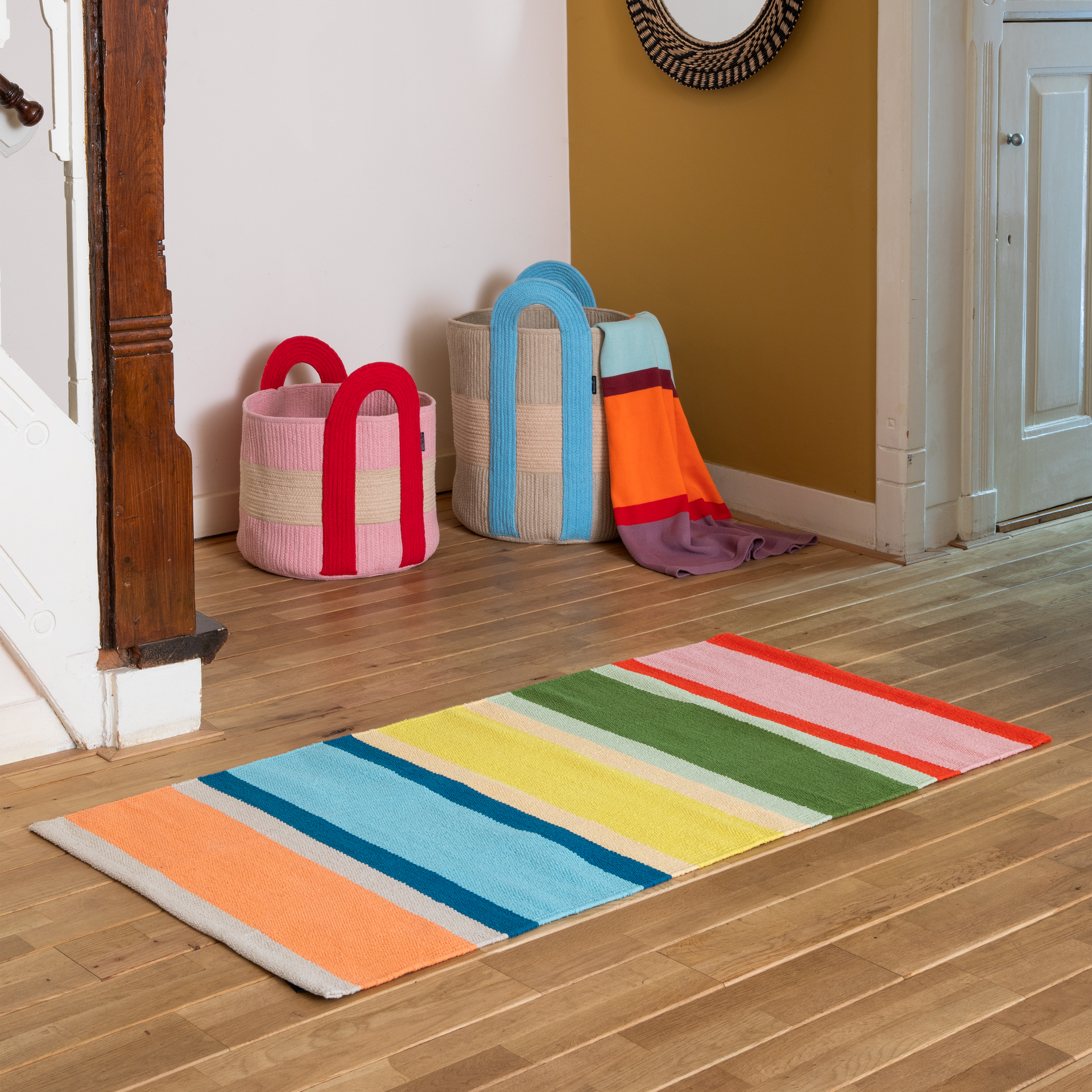 Bunter Teppichläufer mit vertikalen Streifen in kräftigem Rot, zartem Rosa, Olivgrün, leuchtendem Gelb, Türkis, hellem Blau und Korallenorange, getrennt durch schmale cremefarbene Streifen. Kurzflor für fröhliche Akzente.