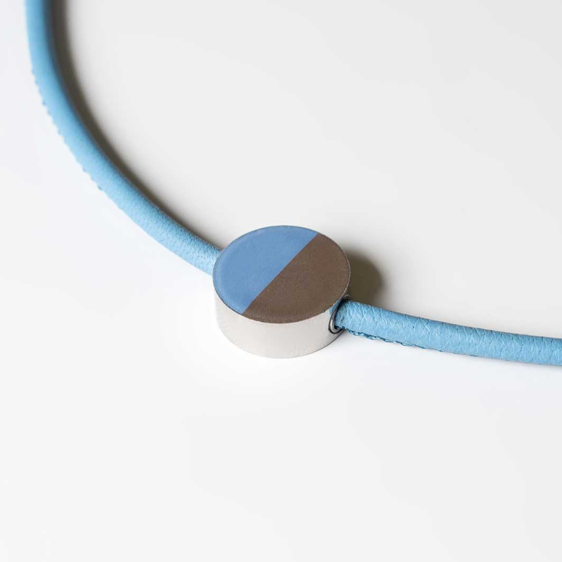 Primo piano di un ciondolo rotondo per gioielli con un nastro blu. Il ciondolo è bicolore, blu e marrone.