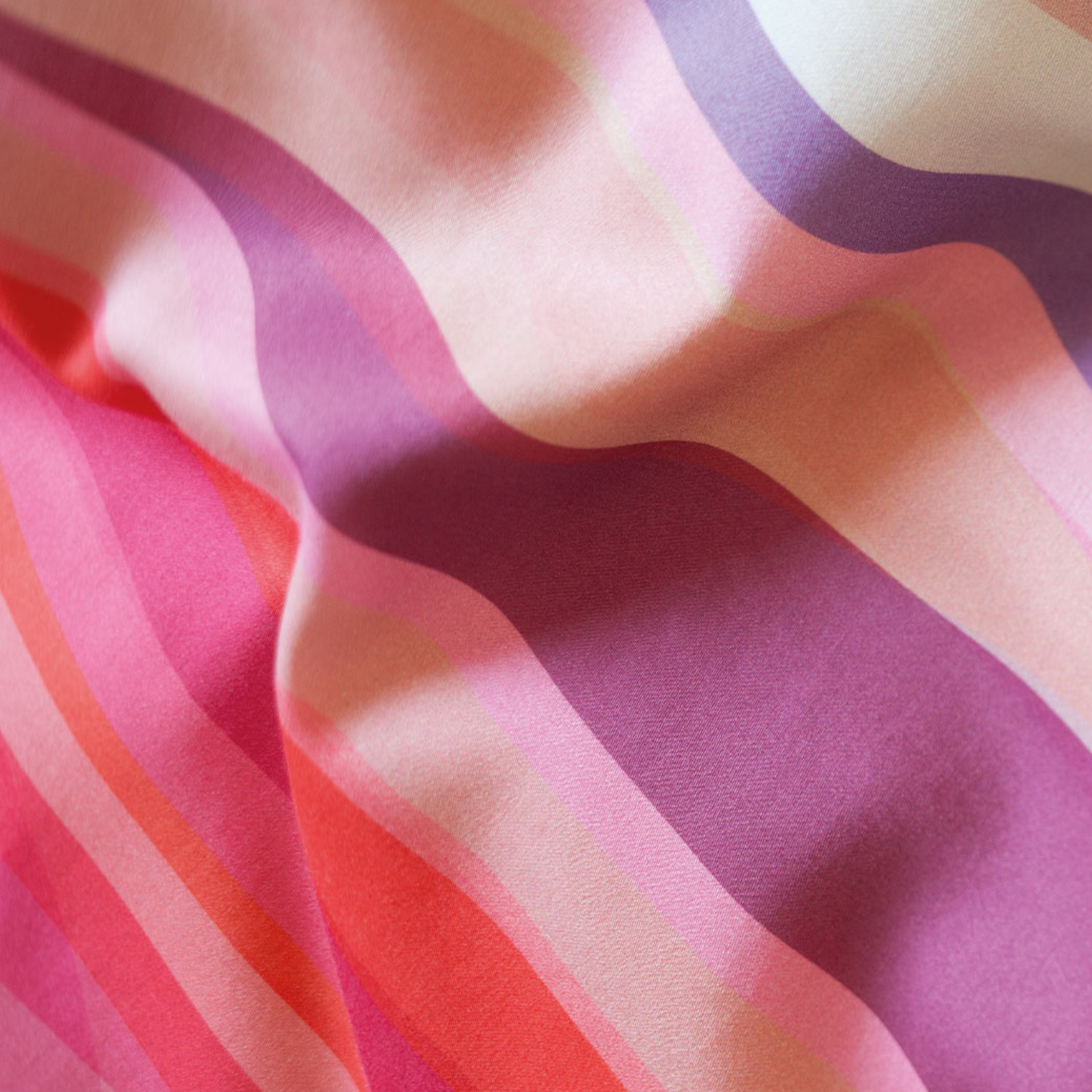 Close-up of 'Mateo' wavy bed linen with wavy stripes in shades of pink, rose and purple.