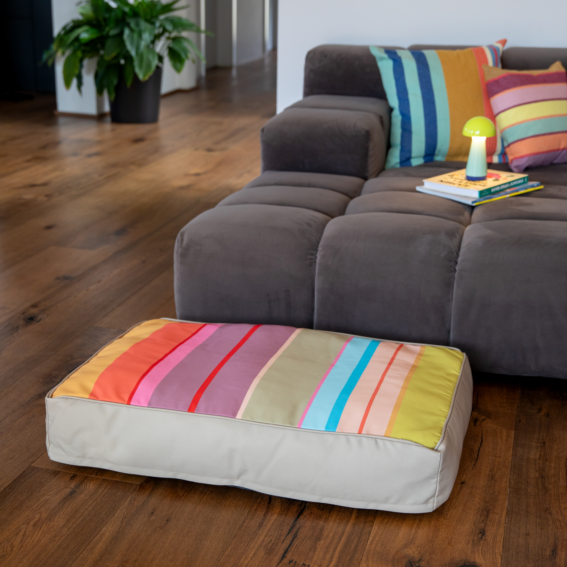Rechteckiges Hundekissen Theo M mit farbenfroher Oberseite: breite horizontale Streifen in leuchtendem Gelb, Orange, Rot, Pink, Violett, Grün und Hellblau. Seiten in neutralem, hellem Beige. Ideal als Ruheplatz.